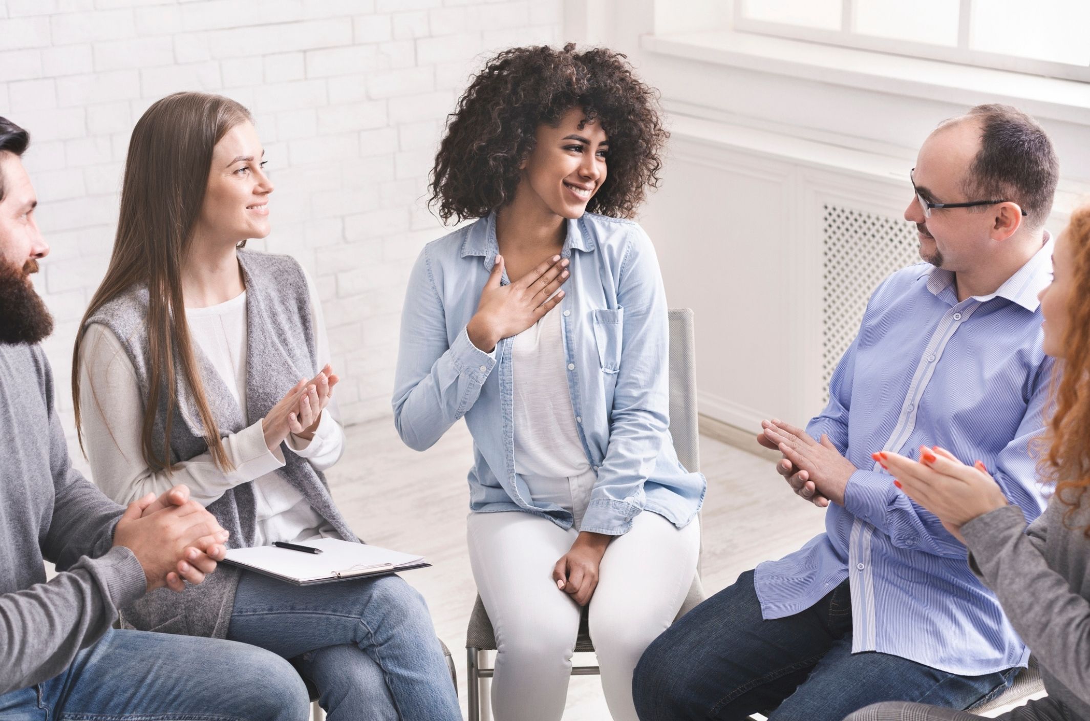 What is addiction? Plus types, symptoms, & treatments happy woman in addiction recovery group shows what addiction treatment is