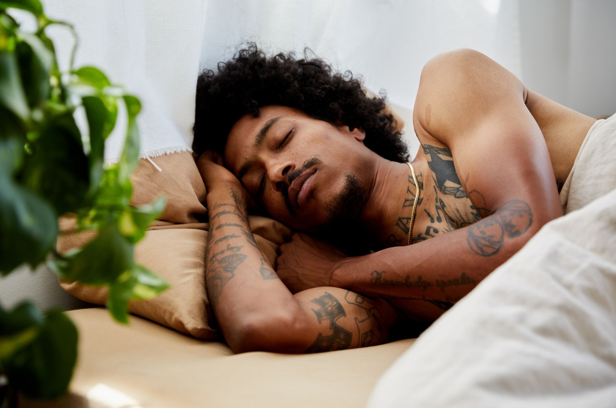 Insomnia: causes, types, symptoms, & treatments young man with tattoos sleeping after treating insomnia symptoms and causes