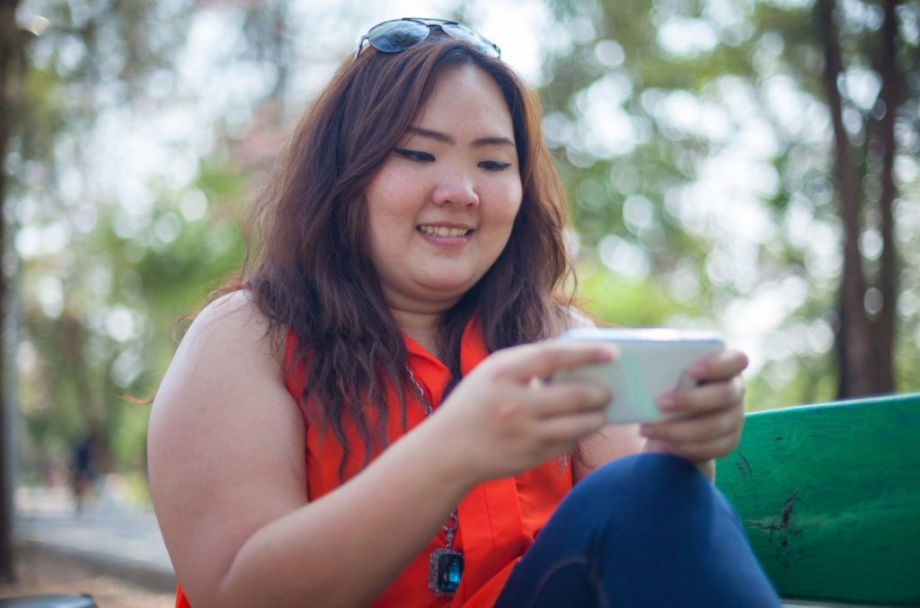 woman in park using social media on phone impacting her mental health