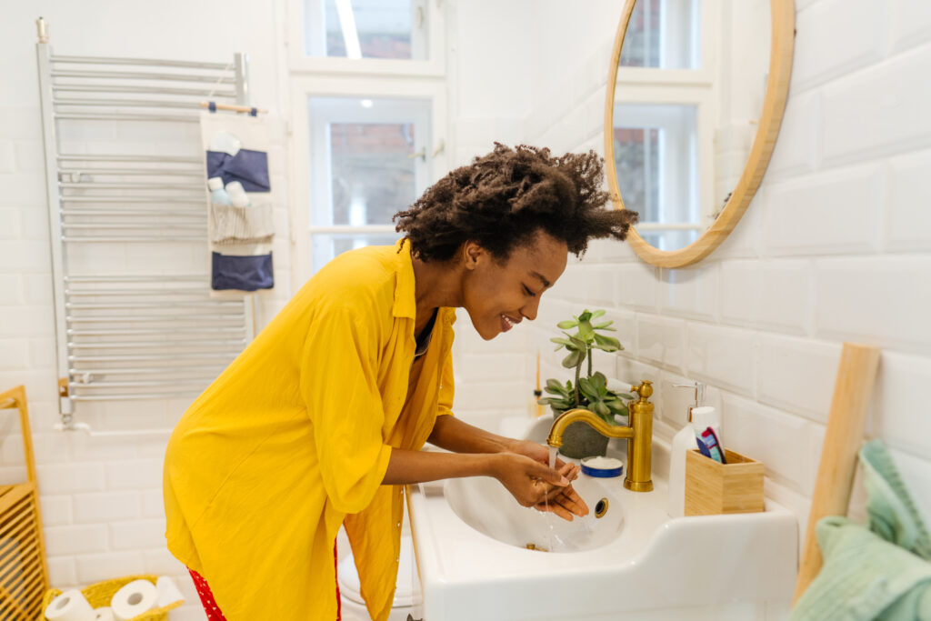 Young woman in a bathroom washing her face