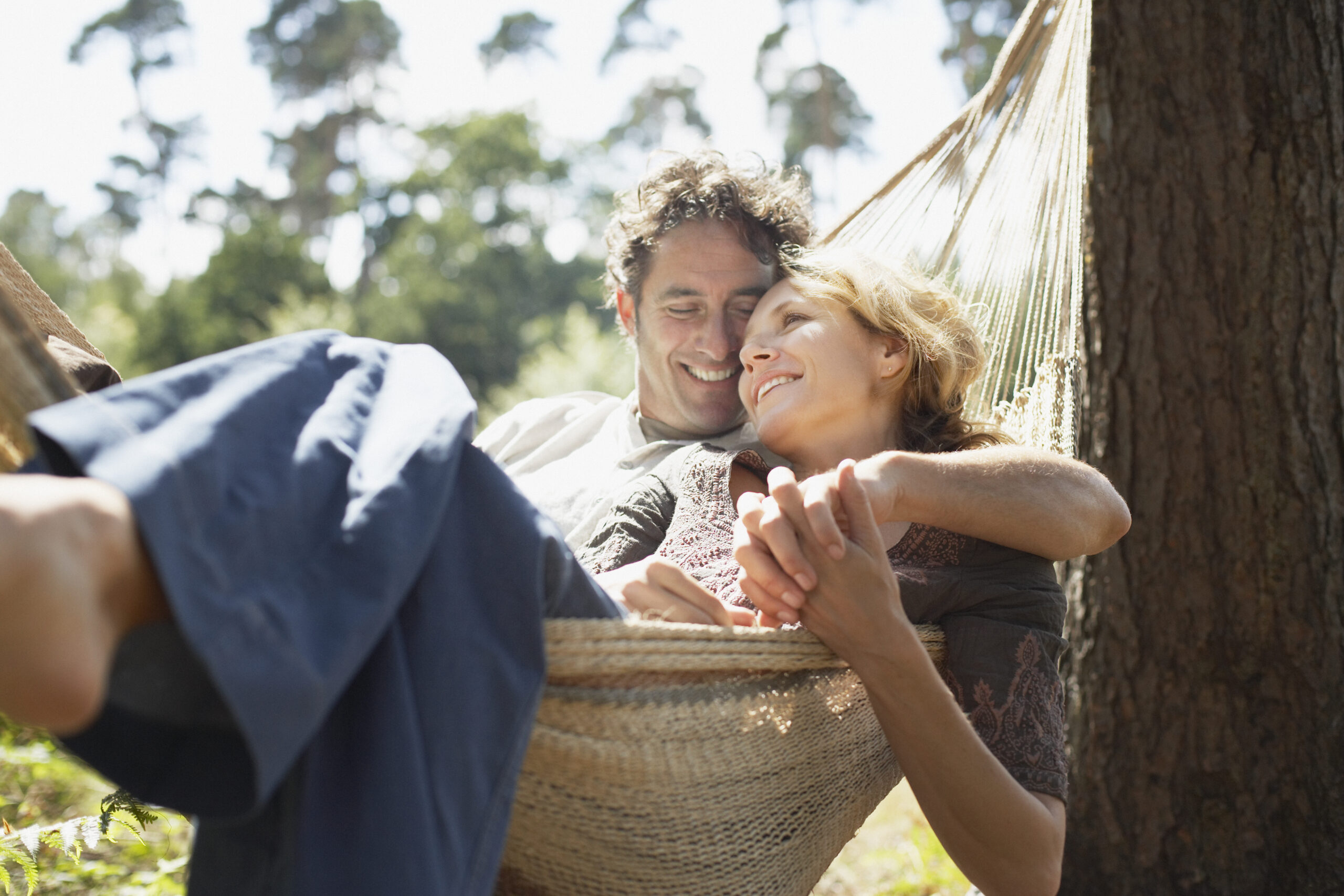 Man and woman snuggling in our outdoor hammock in sunlight