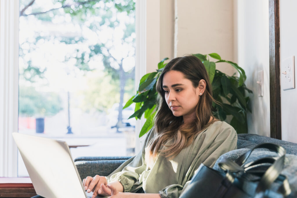 The young adult woman sits on a sofa at the coffee shop
