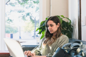 The young adult woman sits on a sofa at the coffee shop